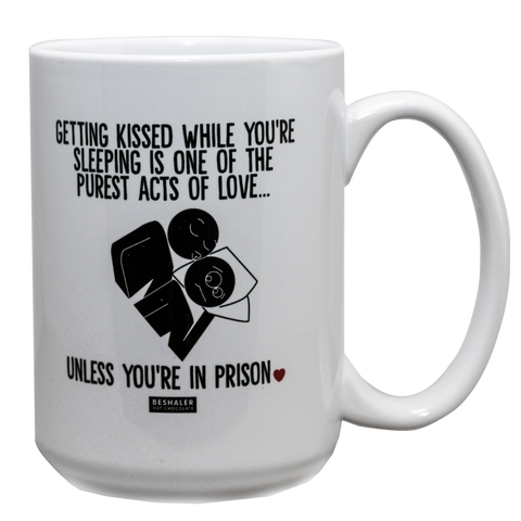 White 15oz ceramic drinking mug with the saying, "Getting kissed while you're sleeping is one of the purest acts of love....unless you're in prison."